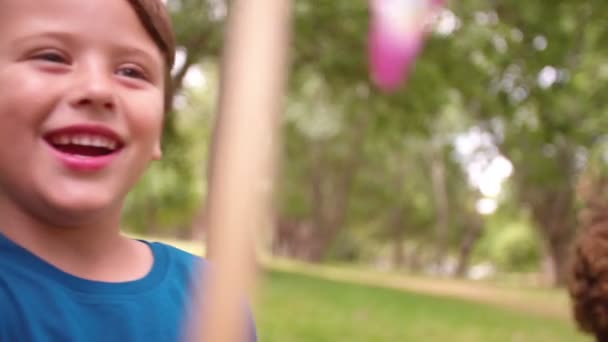 Vänner i en park spelar med färgglada väderkvarnar — Stockvideo