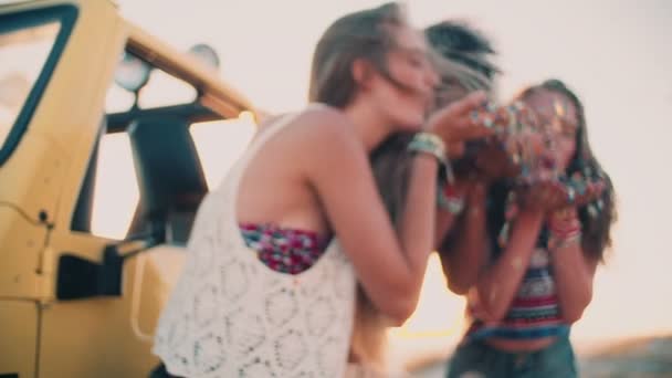 Афро-девушка с друзьями, дующая конфетти — стоковое видео