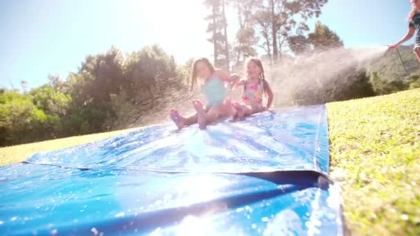 Маленькие девочки скользят по водной горке — стоковое видео