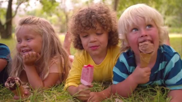 Niños comiendo helados en un parque — Vídeo de stock