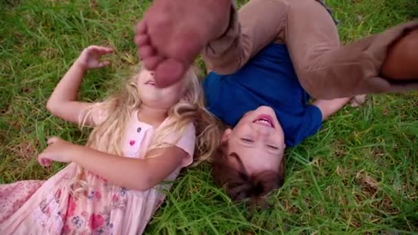 Мальчик катится в траве с девушкой — стоковое видео