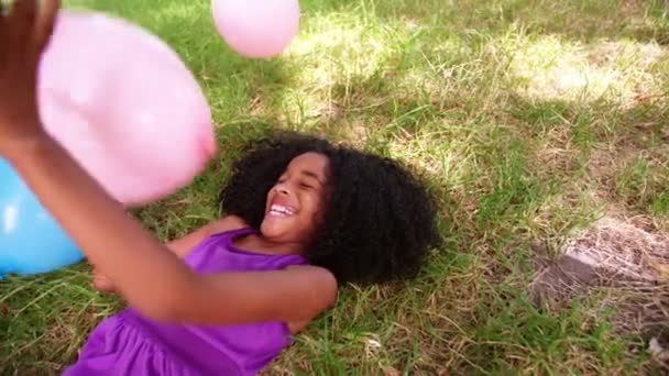 Afro girl playing with balloons on grass — Stock Video