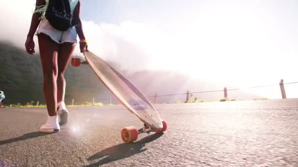 Chica longboarder caminando a lo largo de un camino — Vídeo de stock