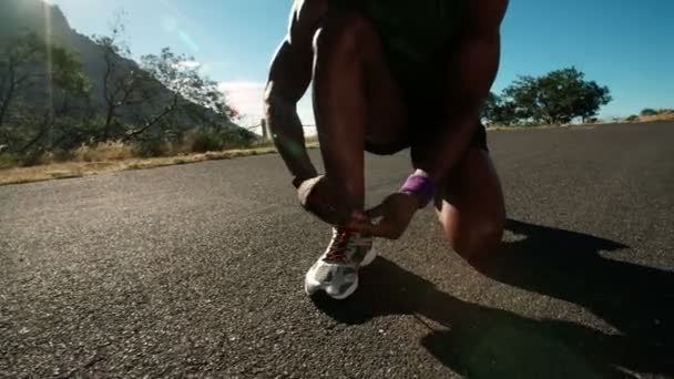 アフリカ系アメリカ人のランナーが彼の靴ひもを結ぶ — ストック動画