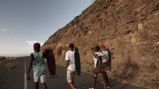 Patinadores adolescentes caminando por el camino — Vídeos de Stock