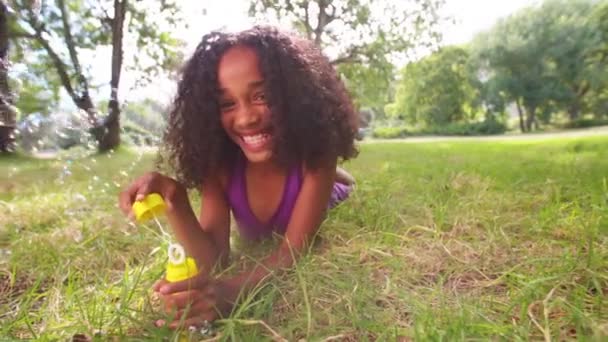 Afro meisje waait bubbels in park — Stockvideo