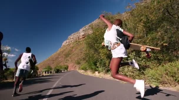 Longboarders corriendo y saltando por una carretera — Vídeo de stock