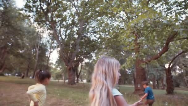 Kinder rennen und jagen Blasen im Park — Stockvideo