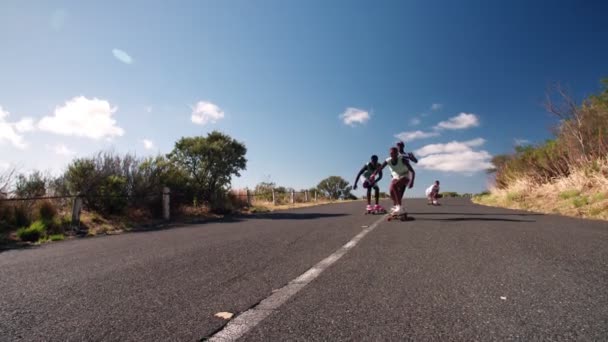 Скейтбордисты мчатся по пустынной дороге — стоковое видео