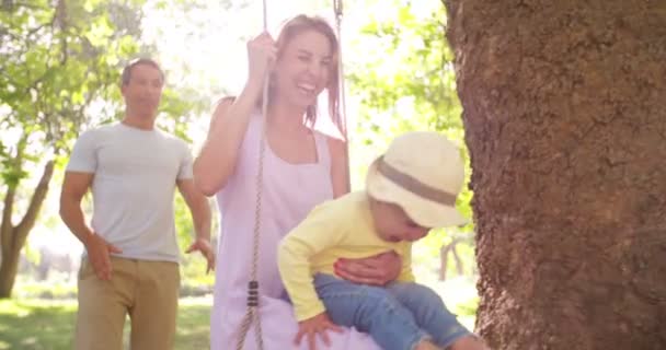 Familj med liten flicka gungar i park — Stockvideo