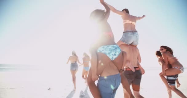 Vänner med piggyback lopp på en strand i sommar — Stockvideo