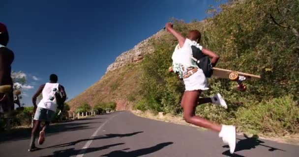 Longboarders τρέξιμο και το άλμα κατά μήκος ενός δρόμου — Αρχείο Βίντεο