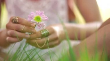 Bir yaz parkta otururken bir çiçek tutan kız