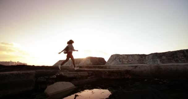 Girl jumping over rock pool — Stock Video