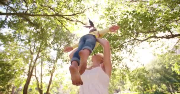 Mother spinning little girl in park