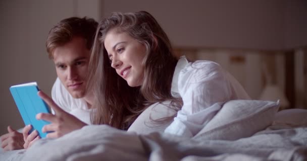 Casal em sua cama compartilhando um tablet digital — Vídeo de Stock