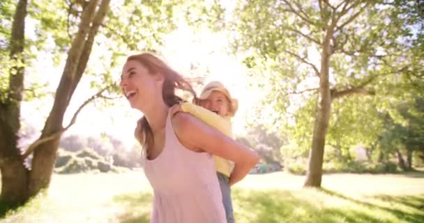 Mamá piggybacking su niño niña en parque — Vídeos de Stock