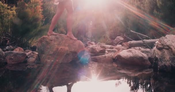 Boho κορίτσι να περπατήσει πέρα από τις πέτρες σε μια λίμνη — Αρχείο Βίντεο