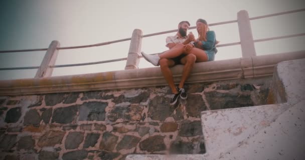 Couple hipster assis sur un mur ensemble — Video