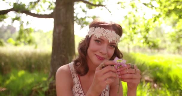 Ragazza hippie sorridente in un parco che tiene il fiore selvatico — Video Stock