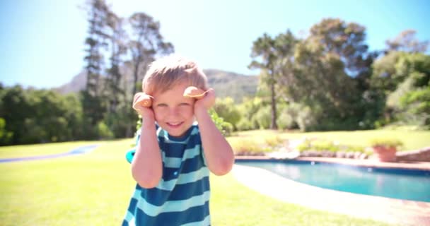 Kleine jongen speels poseren met wortelen als oren — Stockvideo