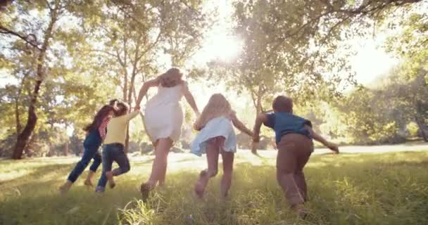 Mulher correndo com crianças através do parque — Vídeo de Stock