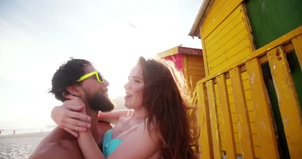 Pareja besándose delante de cabañas de playa — Vídeo de stock