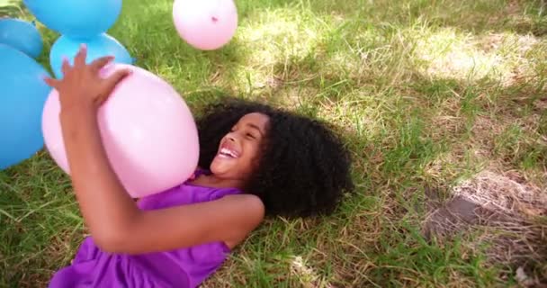 Afro-Mädchen spielt mit Luftballons auf Gras — Stockvideo