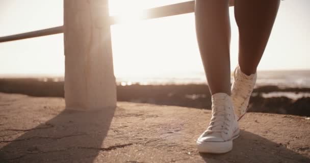 Adolescente vistiendo zapatilla de deporte de pie en la playa — Vídeo de stock