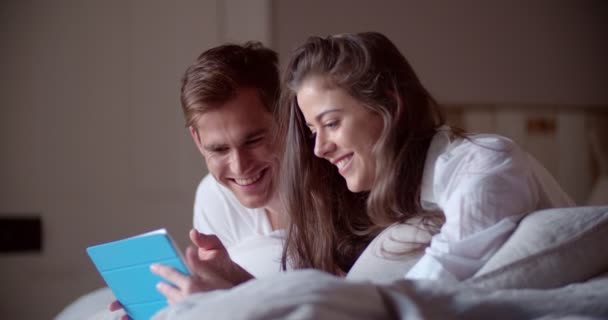 Пара на ліжку, що ділиться цифровим планшетом — стокове відео