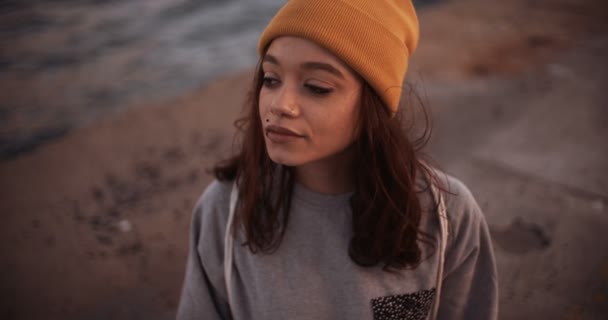 Teen girl in yellow beanie sitting on a pavement — Stock Video