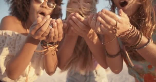 Dziewczyny, dmuchanie konfetti z rąk na plaży — Wideo stockowe