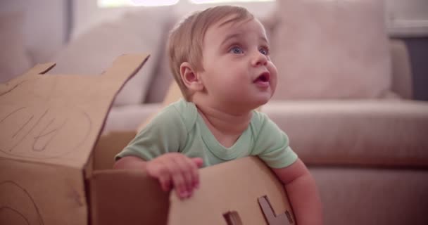 Niño jugando en una caja de cartón — Vídeo de stock