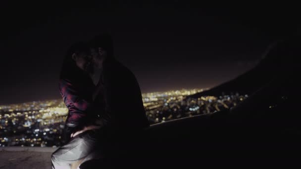 Casal beijando na capota de um carro à noite — Vídeo de Stock