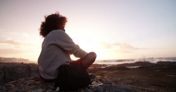 Gün batımında sahilde oturan Afro kız — Stok video