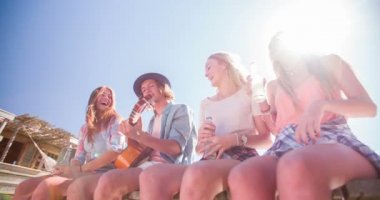 Arkadaşlar birlikte oturup alcopops içiyor ve gülüyorlar.