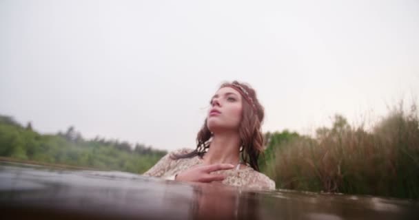 Девушка в кружеве частично погружена в естественное озеро — стоковое видео