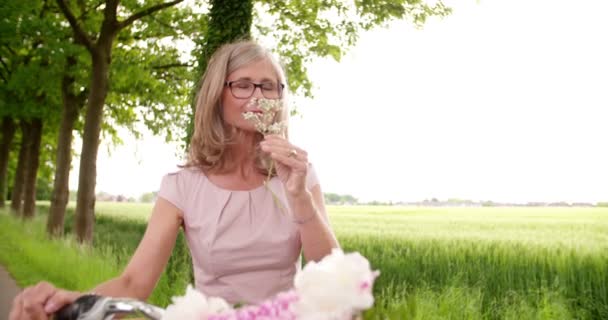 Mogen kvinna att lukta blommor i en park — Stockvideo