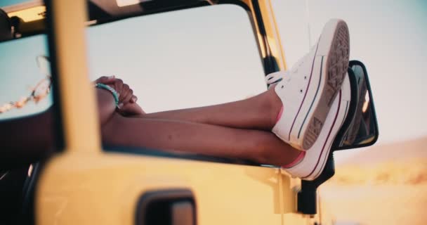 Ноги и ноги торчат из окна машины в дороге — стоковое видео