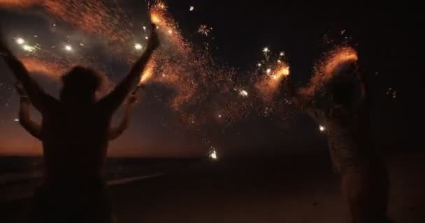 Φίλοι που τρέχει σε μια παραλία με πυροτεχνήματα — Αρχείο Βίντεο
