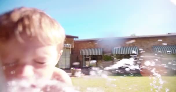 Smiling little boy spraying water — Stock Video