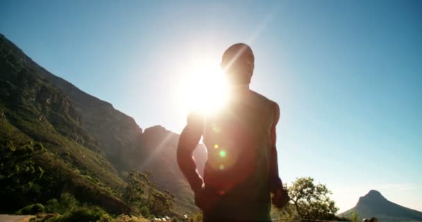 Runner joggen in bergen tegen heldere hemel — Stockvideo