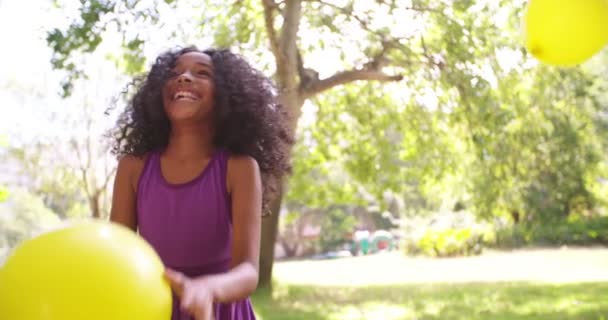 Afro-Mädchen fängt Luftballons im Park Stockvideo