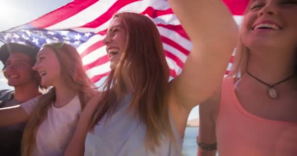 Coole Teen-Freunde, die lächeln und eine amerikanische Flagge halten — Stockvideo