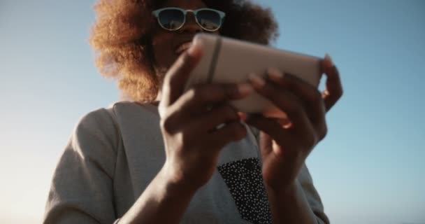 Девушка на пляже использует свой телефон — стоковое видео