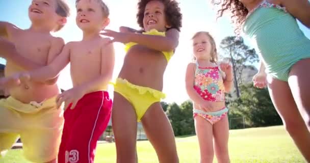 gemischte rassische Gruppe von Kindern, die Wasserballons werfen