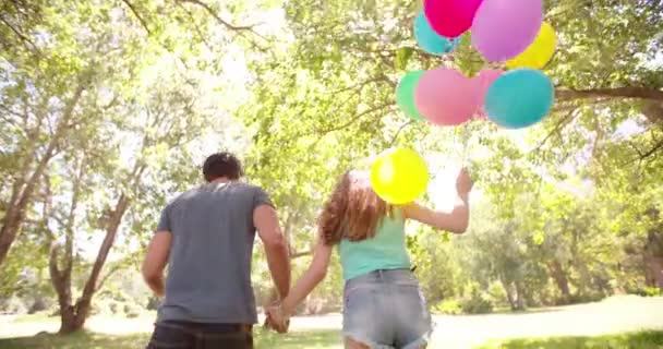 Paar rennt mit Luftballons in Park — Stockvideo