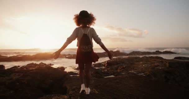 Дівчина крутиться на скелях на пляжі — стокове відео