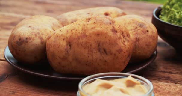 Свежеиспеченный картофель на старинном деревянном столе — стоковое видео