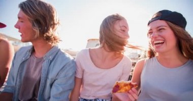Gençler güneş parlaması ile açık havada pizza yeme